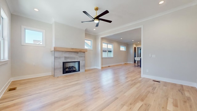 unfurnished living room with baseboards, visible vents, crown molding, light wood-style floors, and a fireplace