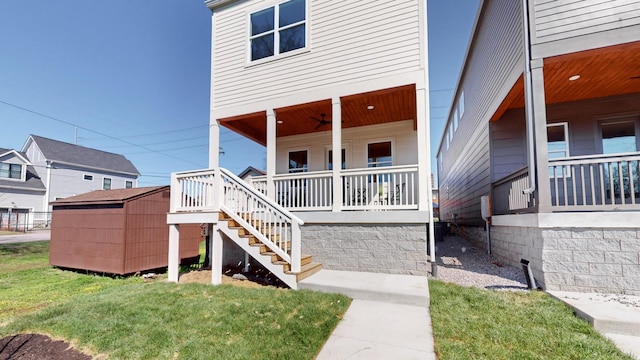 back of house with a storage shed, stairs, a porch, and a lawn