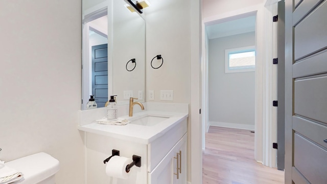 half bathroom featuring baseboards, vanity, toilet, and wood finished floors