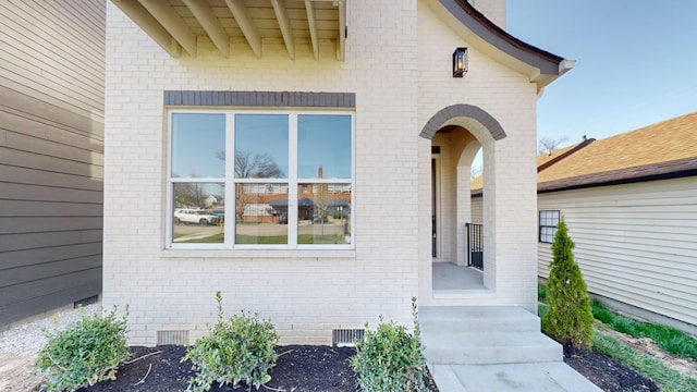 view of exterior entry featuring crawl space and brick siding