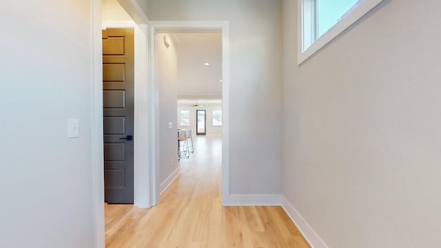 hall featuring light wood-type flooring and baseboards