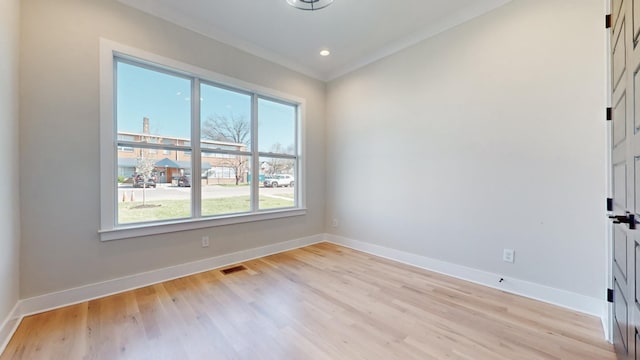 unfurnished room with visible vents, crown molding, light wood finished floors, and baseboards