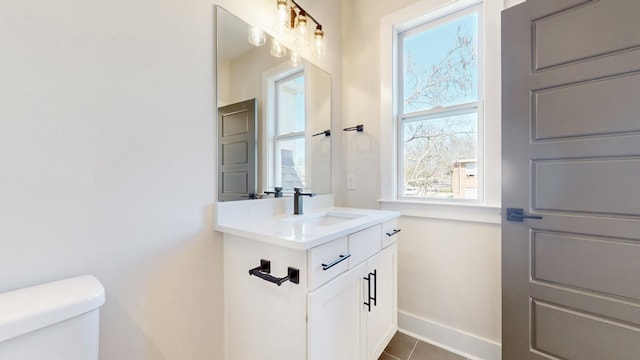 half bath featuring toilet, tile patterned floors, vanity, and baseboards