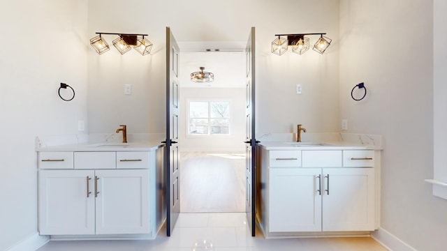 bathroom with baseboards, two vanities, and a sink