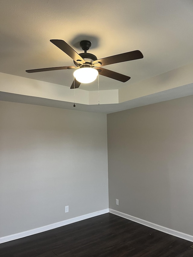 empty room with dark wood-style floors, ceiling fan, and baseboards