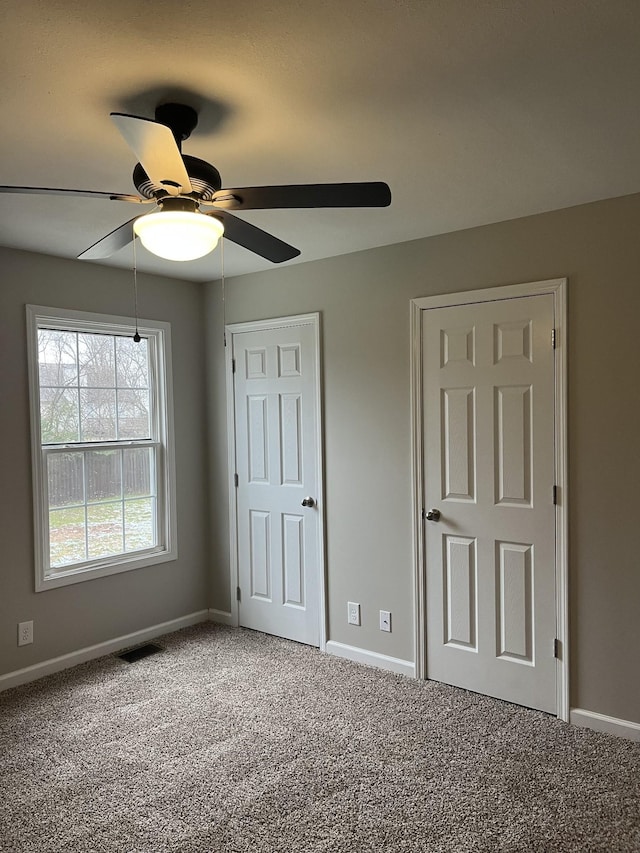 unfurnished bedroom featuring carpet floors, visible vents, ceiling fan, and baseboards