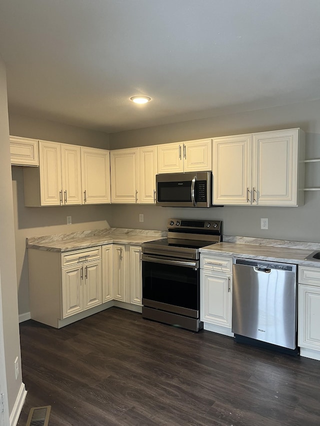 kitchen with dark wood finished floors, stainless steel appliances, light countertops, visible vents, and white cabinetry