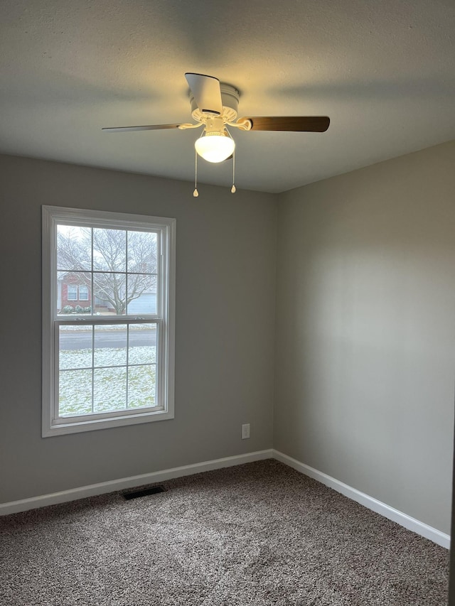 carpeted spare room featuring visible vents, a textured ceiling, baseboards, and a ceiling fan