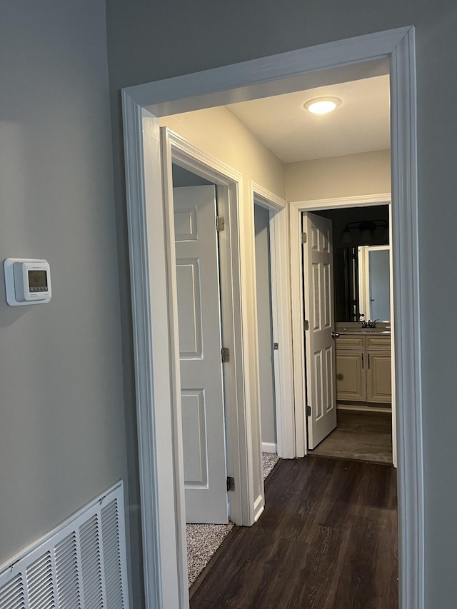 hallway featuring visible vents, dark wood finished floors, and baseboards