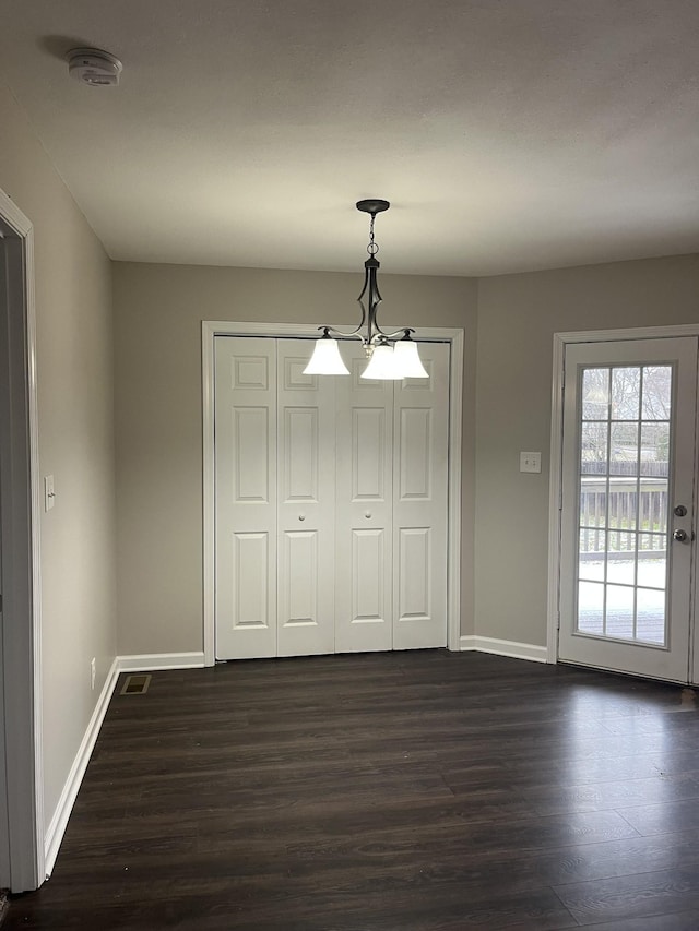 unfurnished dining area featuring dark wood-style floors, visible vents, and baseboards