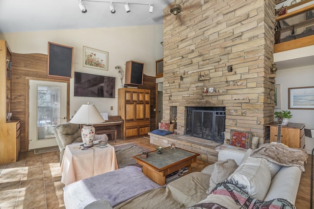 living area with high vaulted ceiling, a fireplace, rail lighting, and light tile patterned flooring