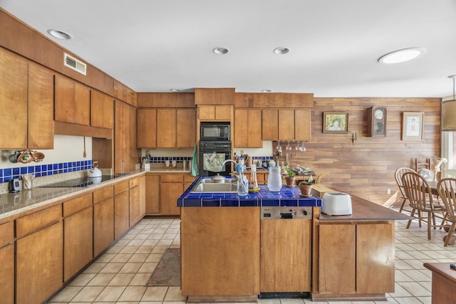 kitchen with a sink, a kitchen island, black appliances, and light tile patterned floors