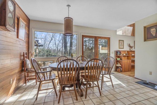 dining area with wooden walls and light tile patterned floors