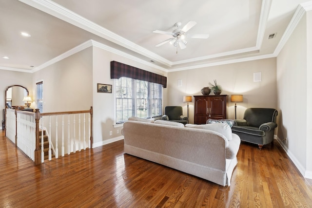 living area with visible vents, baseboards, wood finished floors, and ornamental molding