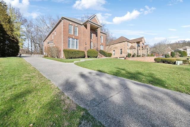 view of front of property with a residential view, brick siding, and a front lawn