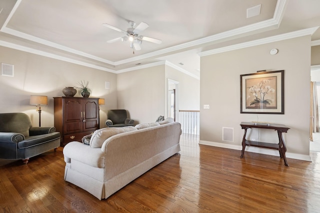 living room featuring crown molding, dark wood finished floors, visible vents, ceiling fan, and baseboards