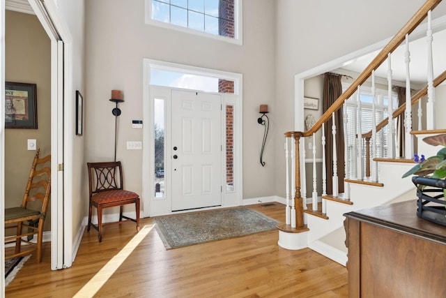 foyer featuring stairway, wood finished floors, a towering ceiling, and baseboards