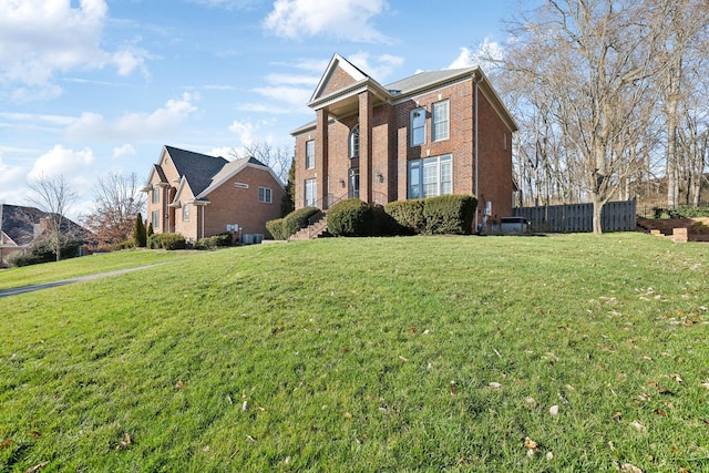 view of front of home featuring a front yard, fence, and brick siding