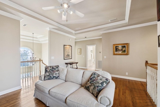 living room with a tray ceiling, dark wood-type flooring, and baseboards