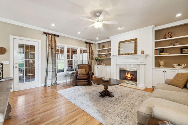 living area with a premium fireplace, light wood-style flooring, and crown molding