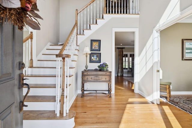 foyer featuring a high ceiling, ornamental molding, wood finished floors, baseboards, and stairs