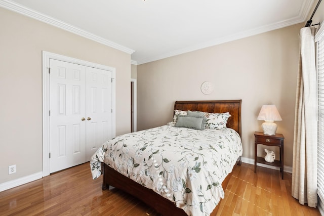 bedroom with crown molding, a closet, light wood-type flooring, and baseboards