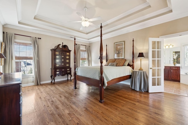 bedroom featuring a raised ceiling, multiple windows, and wood finished floors