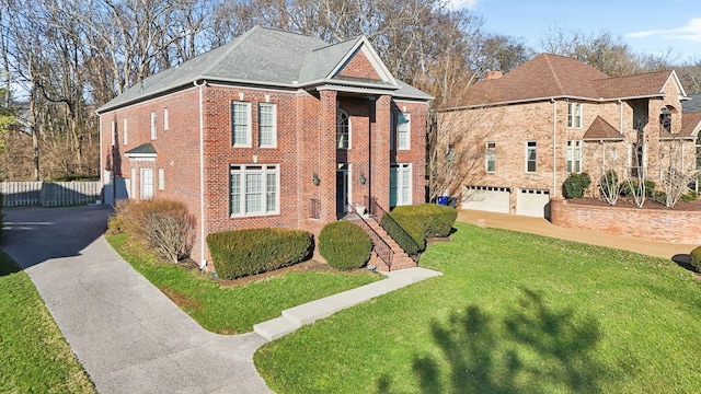 view of front of house featuring a front yard, brick siding, and driveway