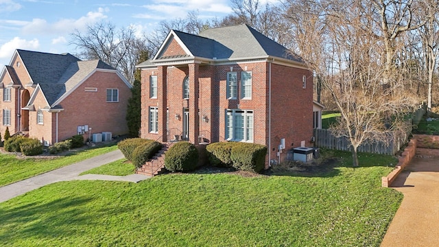 view of front of property featuring brick siding, a front yard, and cooling unit