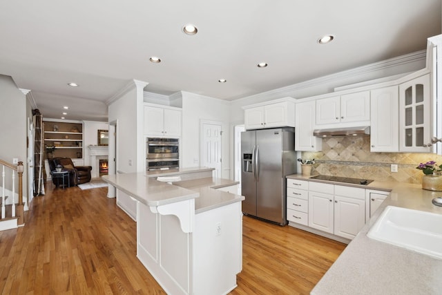 kitchen with glass insert cabinets, white cabinetry, stainless steel appliances, and a sink