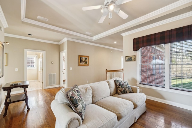 living room featuring baseboards, crown molding, visible vents, and wood finished floors