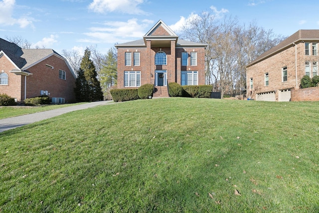 view of front of home with an attached garage, central air condition unit, a front yard, and brick siding