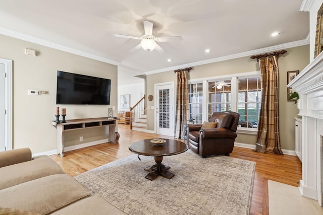 living area with light wood-style floors, ceiling fan, crown molding, and a fireplace with flush hearth