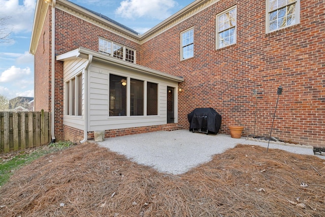 rear view of property featuring brick siding, a patio area, and fence