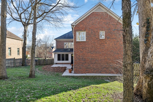 view of side of property with a yard, brick siding, fence, and a patio