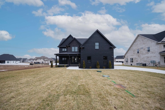 view of front facade with a residential view, brick siding, central AC, and a front lawn