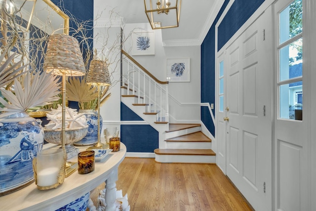 entrance foyer with crown molding, stairway, and wood finished floors