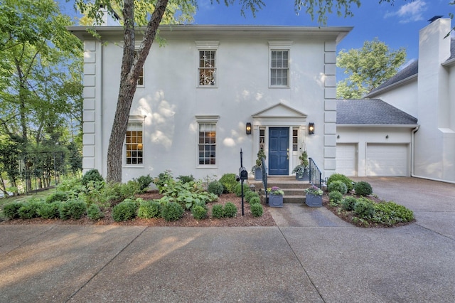 view of front facade with a garage, driveway, and stucco siding