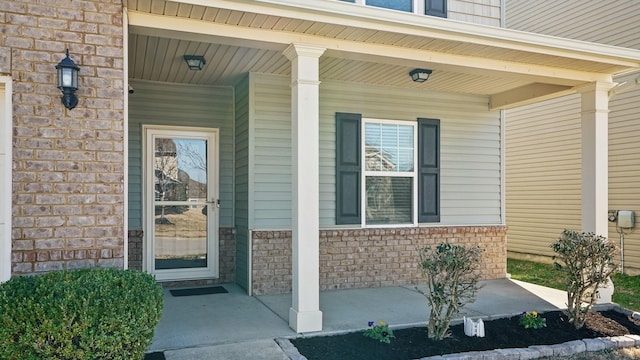 doorway to property featuring covered porch and brick siding