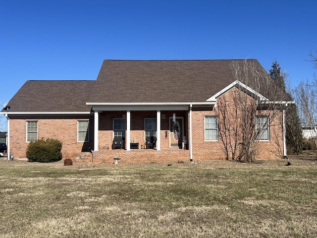 view of front of property with a front yard, brick siding, and roof with shingles