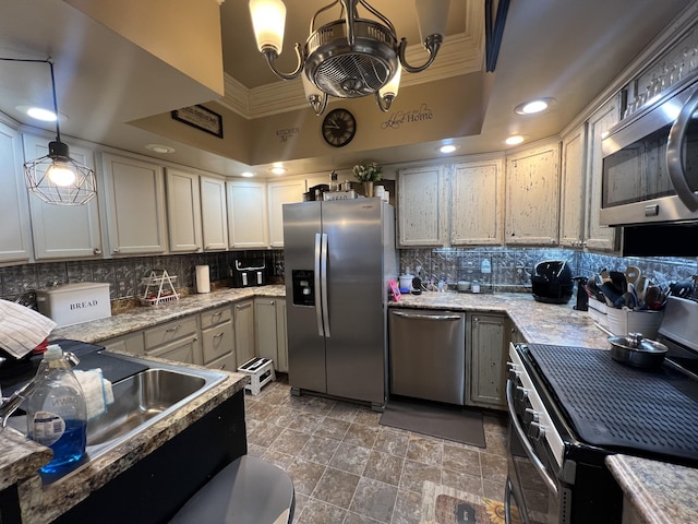 kitchen with appliances with stainless steel finishes, a tray ceiling, ornamental molding, and tasteful backsplash