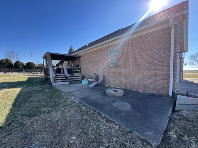 view of property exterior with brick siding, a lawn, and a deck