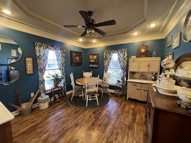 dining area with a tray ceiling, dark wood-style flooring, ornamental molding, a ceiling fan, and baseboards