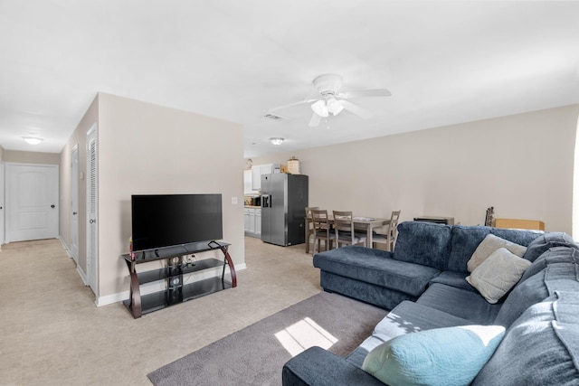 living room with a ceiling fan, visible vents, and baseboards