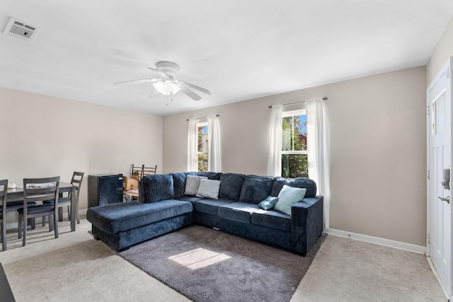 living area with baseboards, visible vents, and ceiling fan