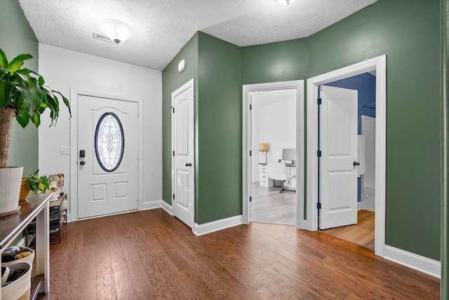 entryway featuring a textured ceiling, hardwood / wood-style floors, and baseboards