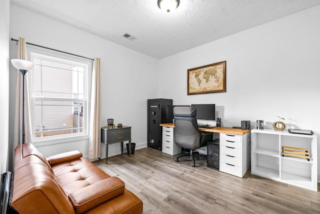 office featuring a textured ceiling, visible vents, and light wood-style floors