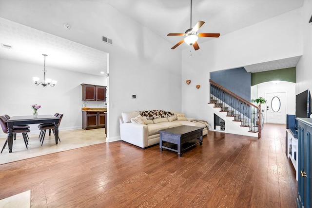 living room with visible vents, baseboards, hardwood / wood-style flooring, stairway, and a high ceiling