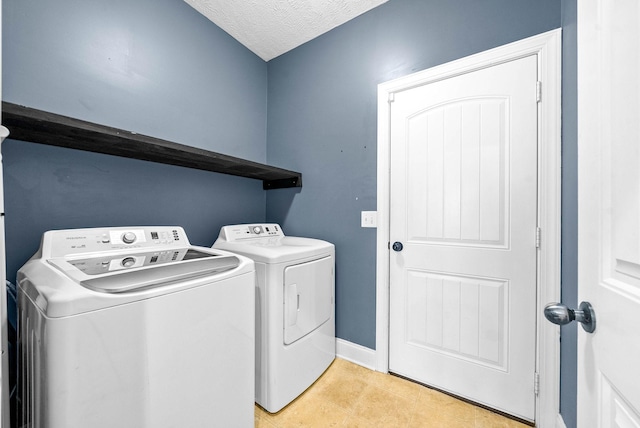 washroom with a textured ceiling, laundry area, washing machine and dryer, and baseboards