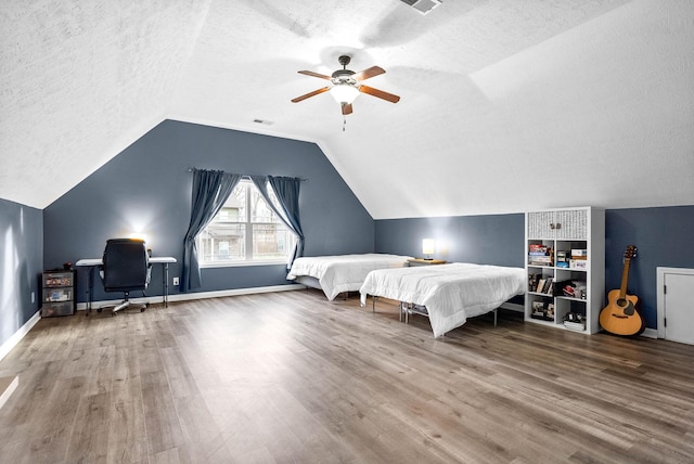 bedroom featuring a textured ceiling, ceiling fan, wood finished floors, and lofted ceiling